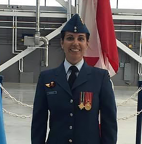 Jan Kennedy in uniform standing in front of Canadian flag